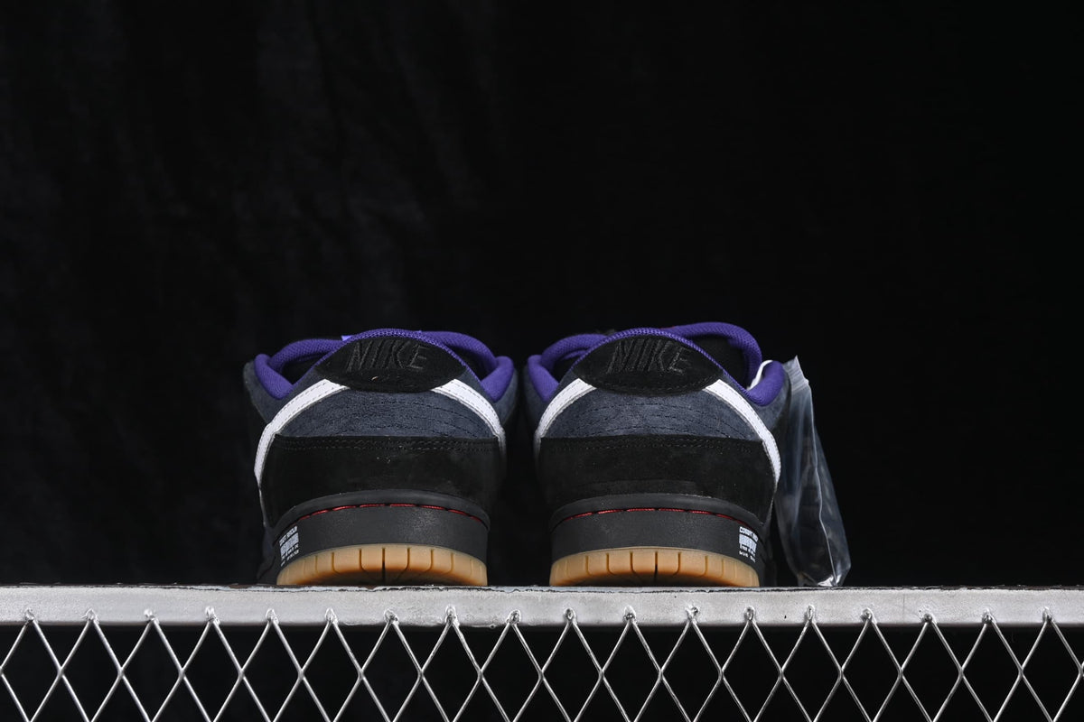 Rear view of the Nike SB Dunk Low sneakers showing black heel panels, white heel accents, and purple collar lining.