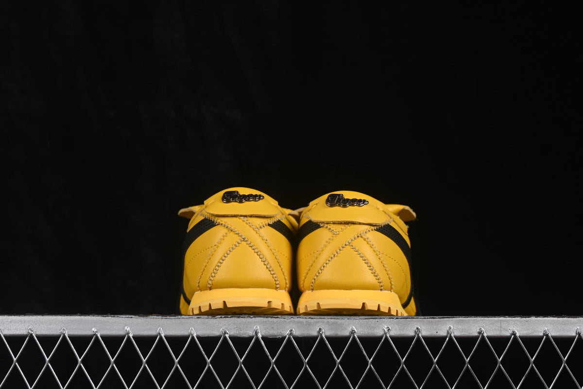Rear view showing the yellow heel panels, stitched detailing, black accents, and rubber outsole