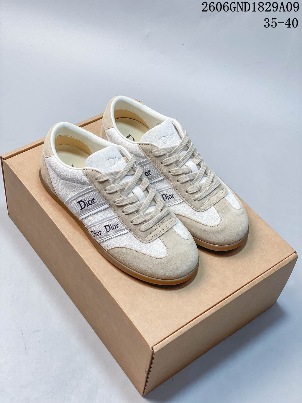 Pair of cream and beige Dior-lettered low-top sneakers on a box
