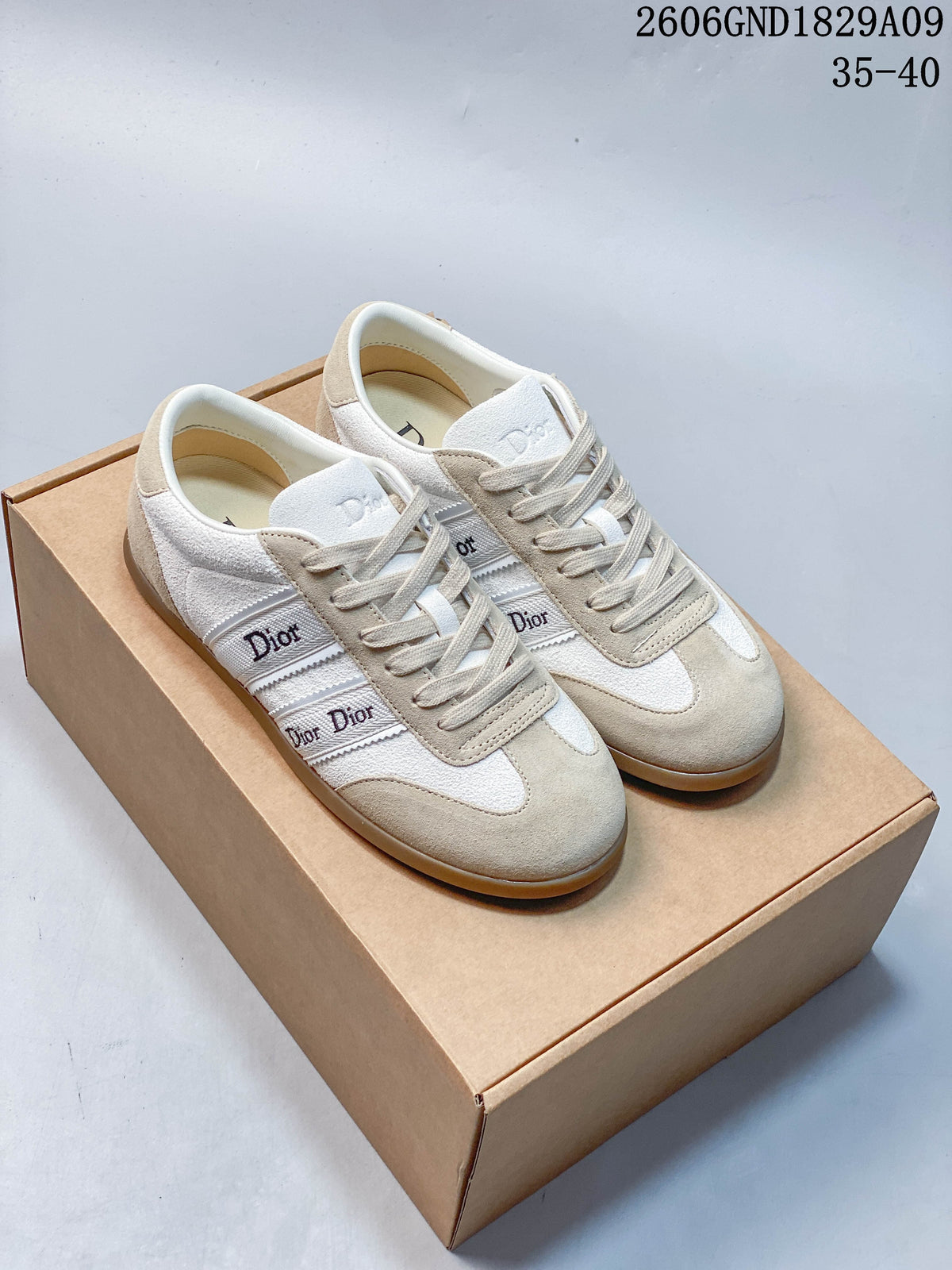 Pair of cream and beige Dior-lettered low-top sneakers on a box