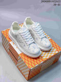 Pair of white Beverly Hills low-top sneakers with multicolored monogram-style patterning beside a patterned box