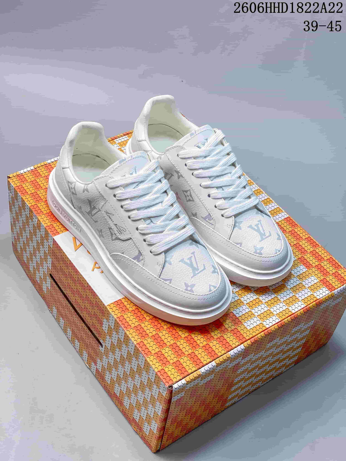 Pair of white Beverly Hills low-top sneakers with multicolored monogram-style patterning beside a patterned box