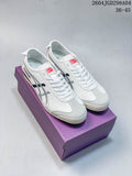 Pair of white Onitsuka Tiger Mexico 66 Deluxe sneakers with silver side stripes and gray toe overlays, shown on a purple box.