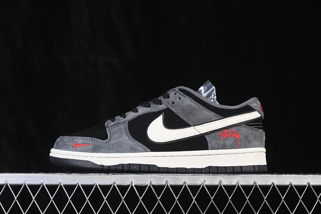 Side profile of a black and grey low-top sneaker with a white side logo and red accents