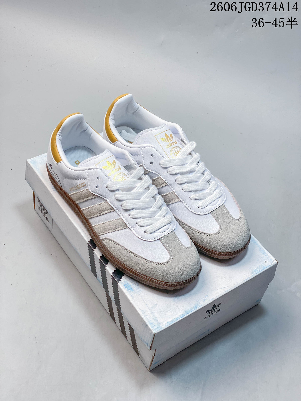 Pair of white Adidas Originals low-top sneakers with gray overlays, gold heel tabs, and brown-toned outsoles on a shoebox