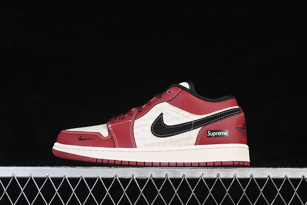 Side view of a red, black, and white Air Jordan 1 Low sneaker with patterned white panels, black side detailing, and a red outsole.