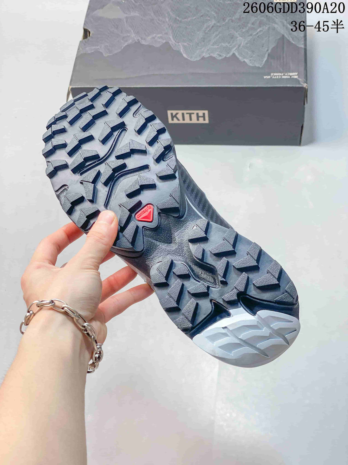Close-up of the Salomon XT-4K shoe's deeply lugged outsole beside a Kith box.