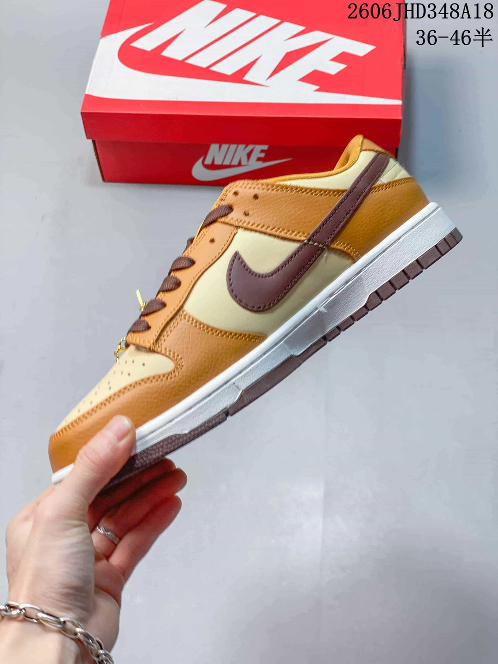 Side profile of the cream and tan sneaker with a brown Swoosh