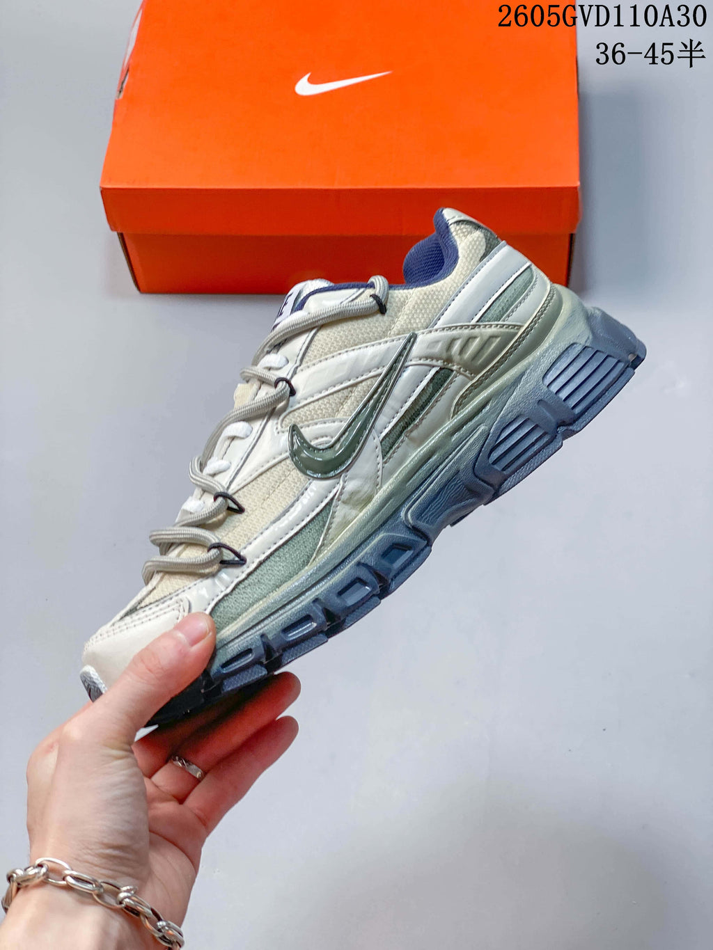 Side profile of a Nike Initiator sneaker with cream and silver-toned panels and blue-gray outsole