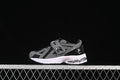 Black and gray kids’ sneaker with hook-and-loop straps and a white midsole, shown against a dark background.