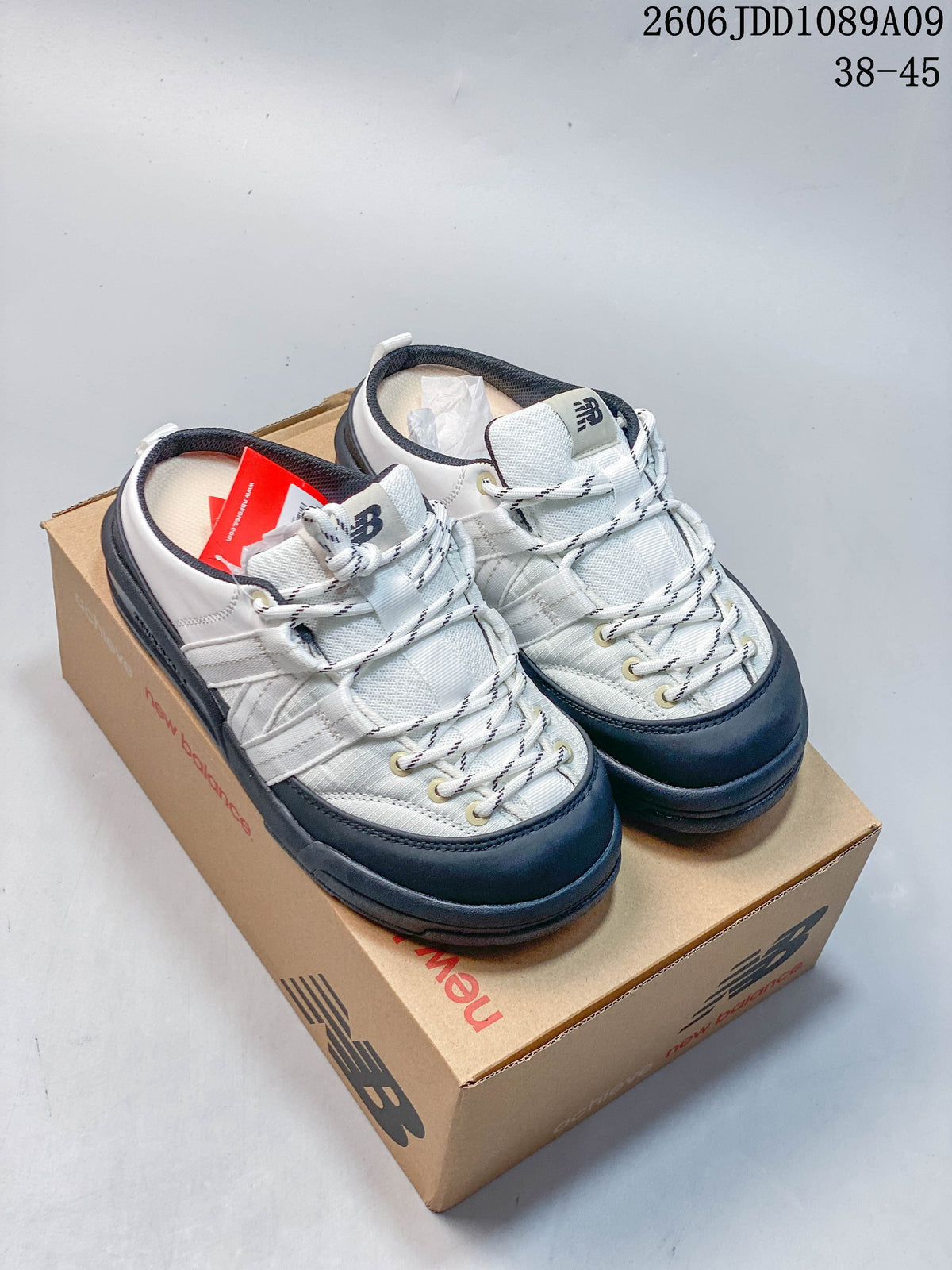 White and navy New Balance Terrace Mule shoes shown together on a shoebox.