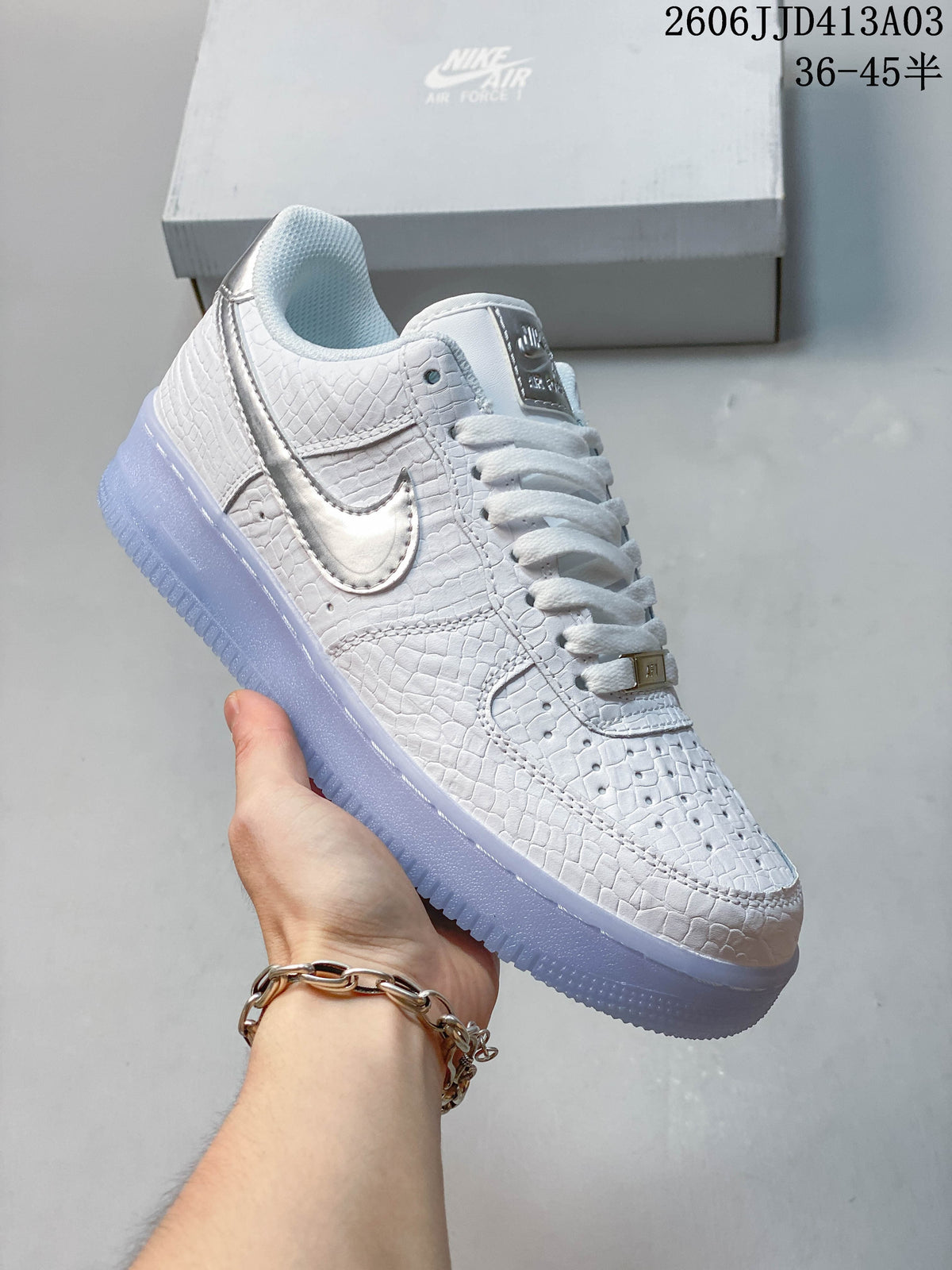 Side view of a white textured low-top sneaker with a metallic-look Swoosh and pale blue outsole.