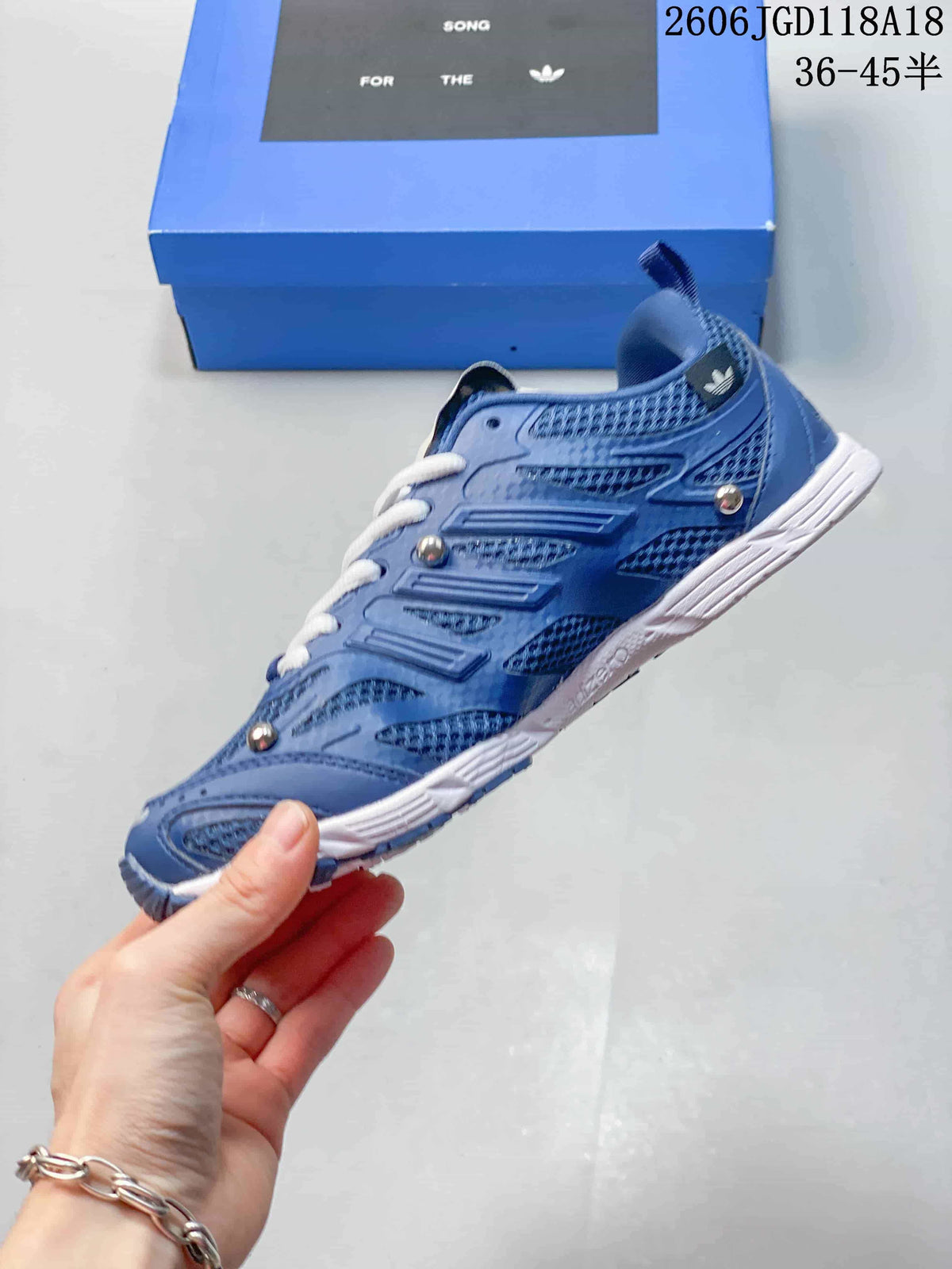 Side view of the blue sneaker with three-stripe details and silver-tone accents.