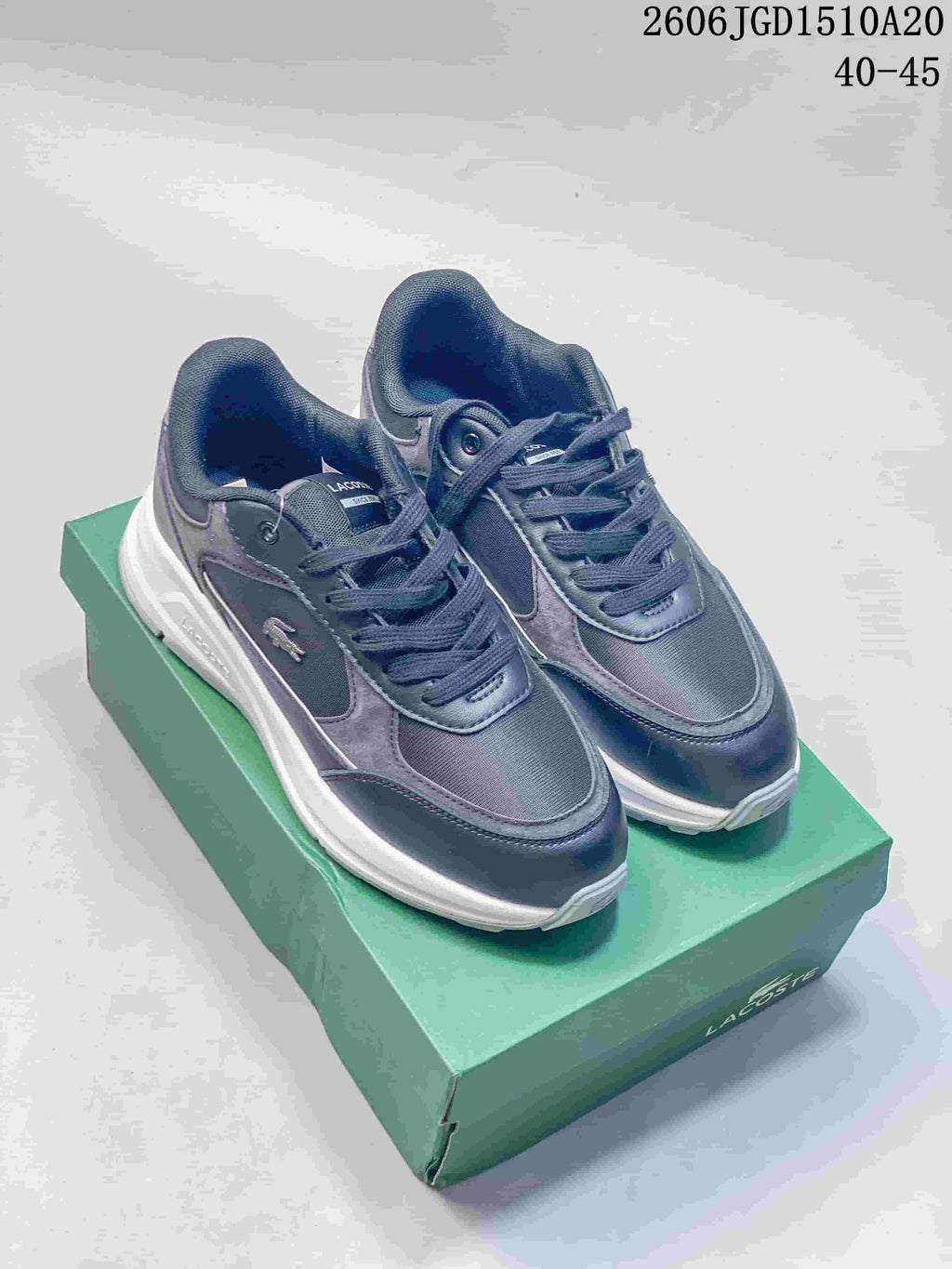 Pair of grey and navy Lacoste low-top sneakers shown from above on a green shoebox.