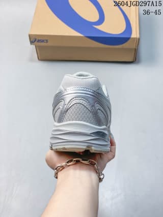 Rear view showing the heel structure, textured upper, and segmented outsole of the white and silver sneaker.