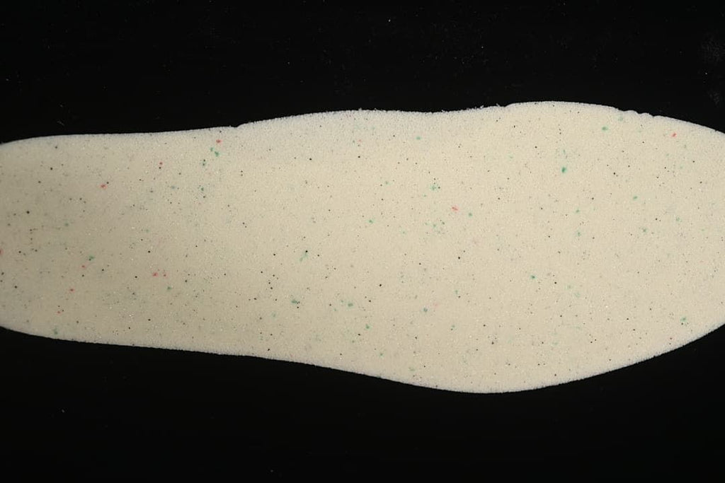 Close-up view of a light-colored shoe insole with small colored speckles.
