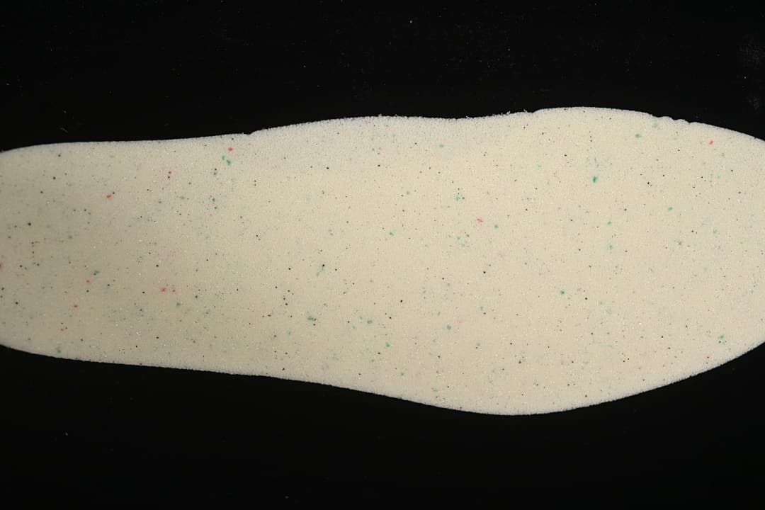 Close-up view of a light-colored shoe insole with small colored speckles.