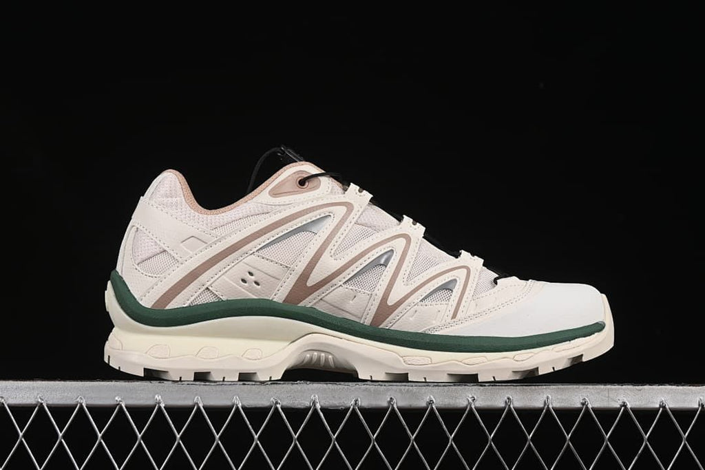 Side profile showing the layered upper, dark green accent, and lugged sole.