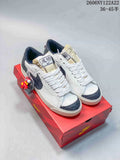Pair of white Nike Blazer Low Jumbo sneakers with dark gray patterned accents, displayed on a red shoe box.