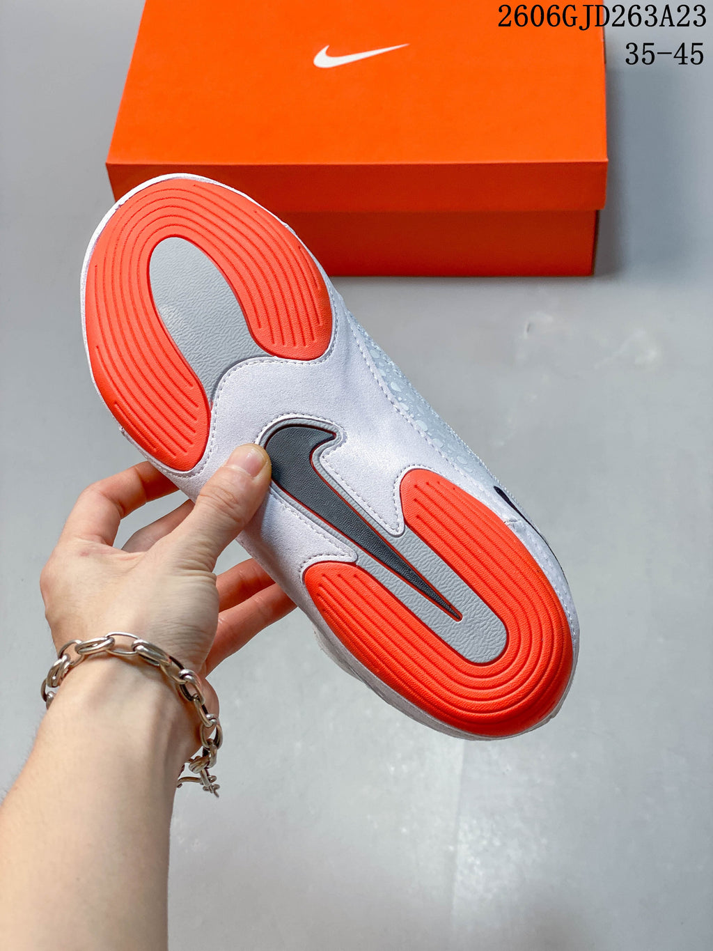 Underside of a Nike Inflict 4 shoe showing a gray and bright orange outsole.