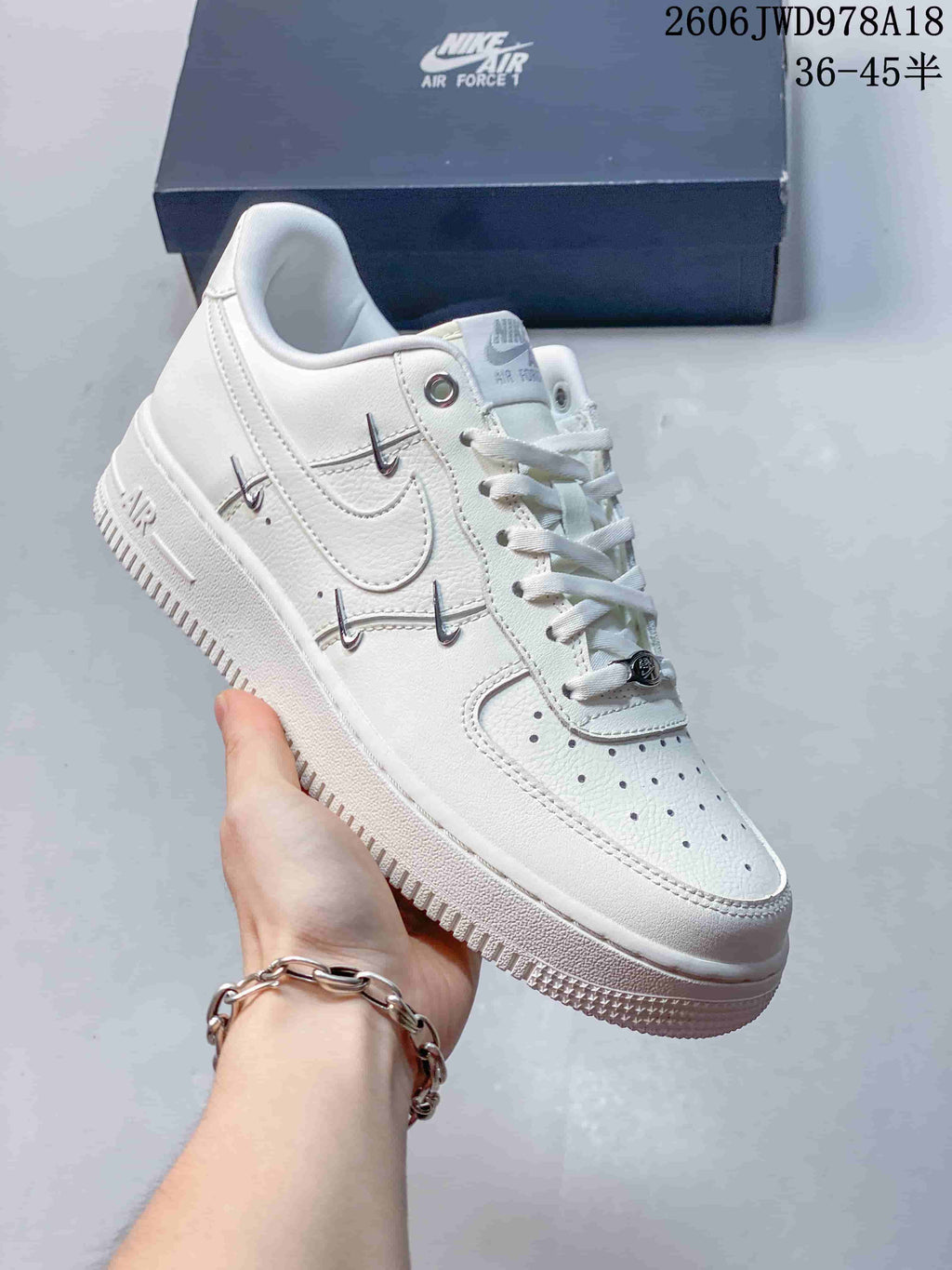 Angled side view of a white Nike Air Force 1 sneaker with metallic accents
