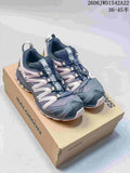Pair of navy, gray, and pale pink Salomon XA Pro trail-style sneakers on a branded box
