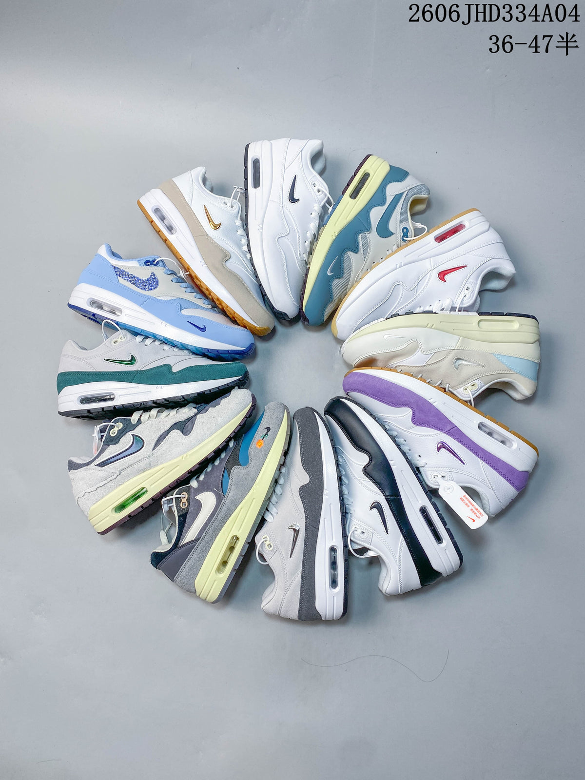White Nike Air Max 1 sneaker with dark teal overlays and a reflective green Swoosh.