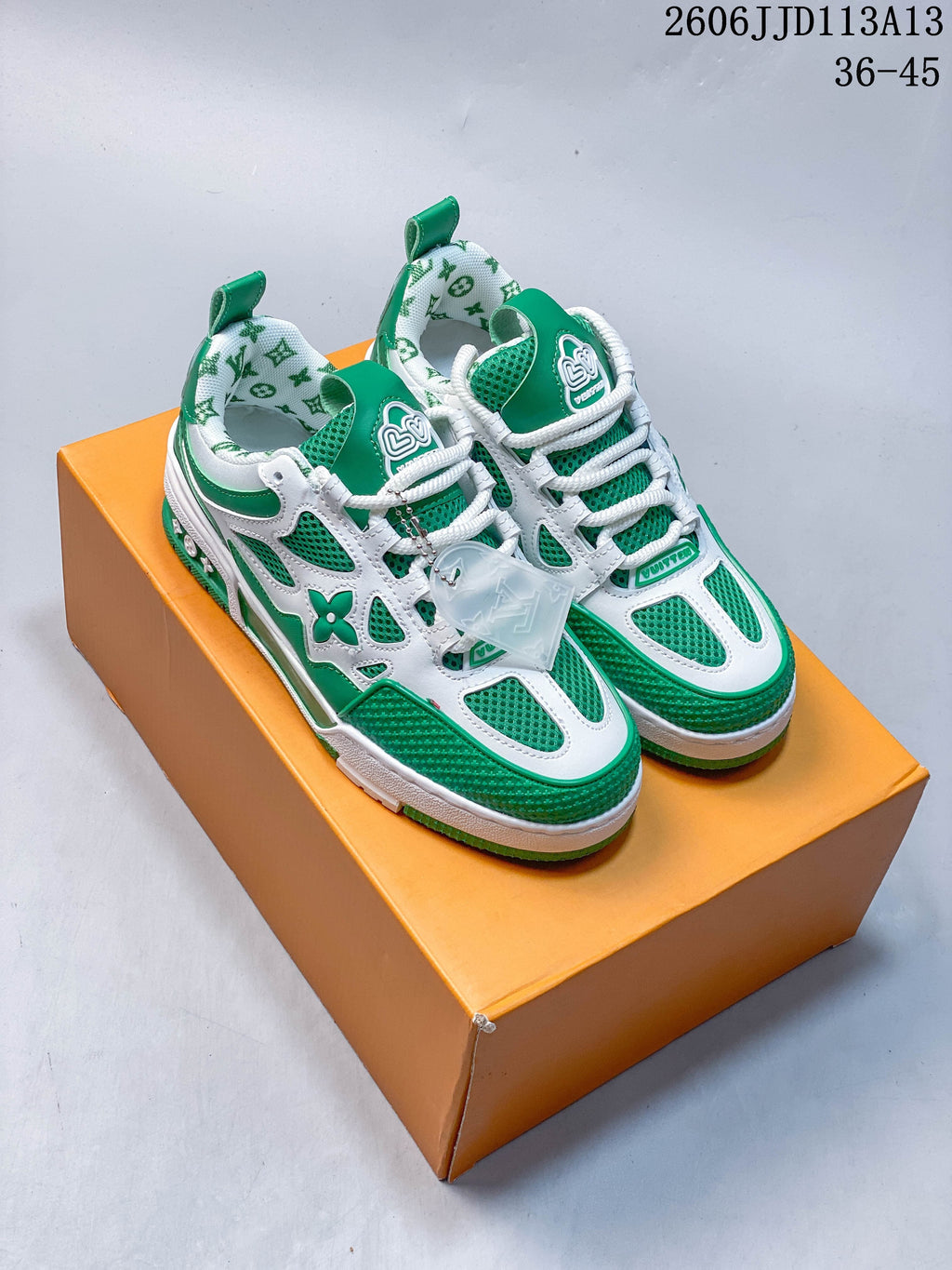 Pair of green and white low-top sneakers with mesh panels and layered overlays, shown on an orange box.