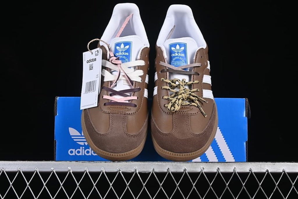 Front view of the pair showing brown uppers, white stripes, and varied laces.