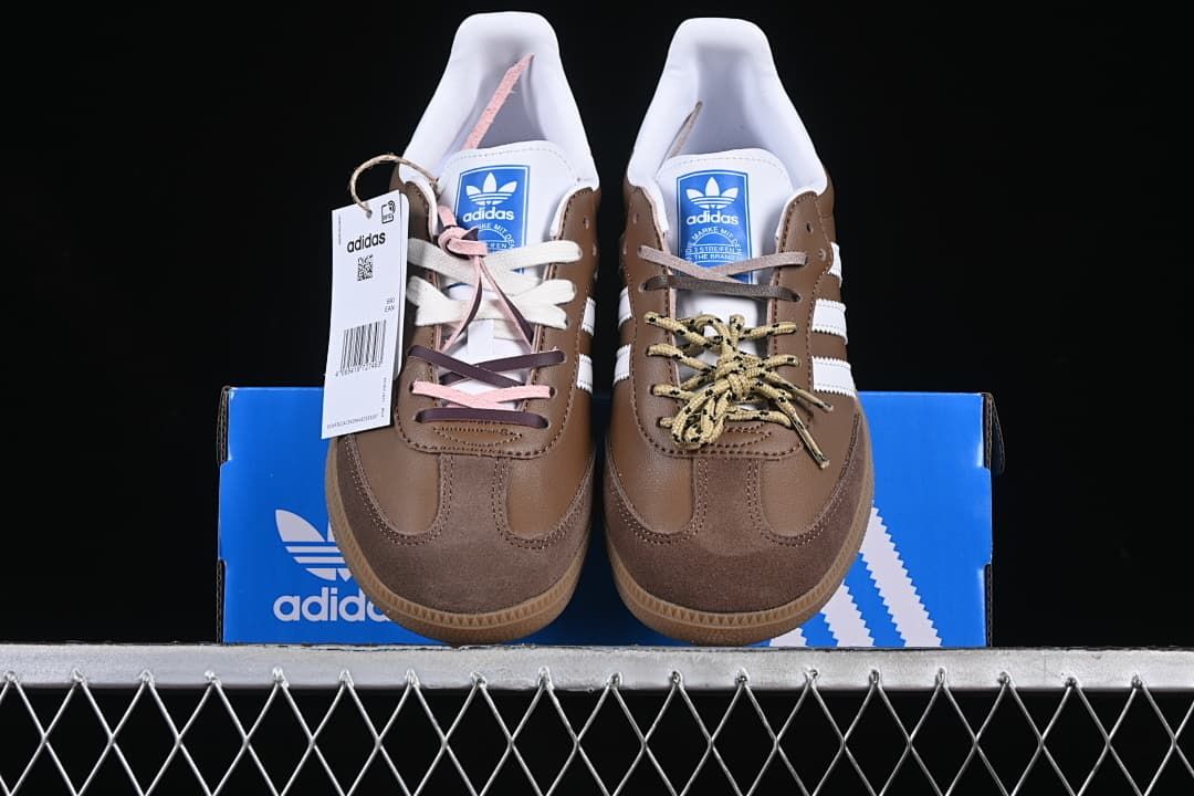 Front view of the pair showing brown uppers, white stripes, and varied laces.