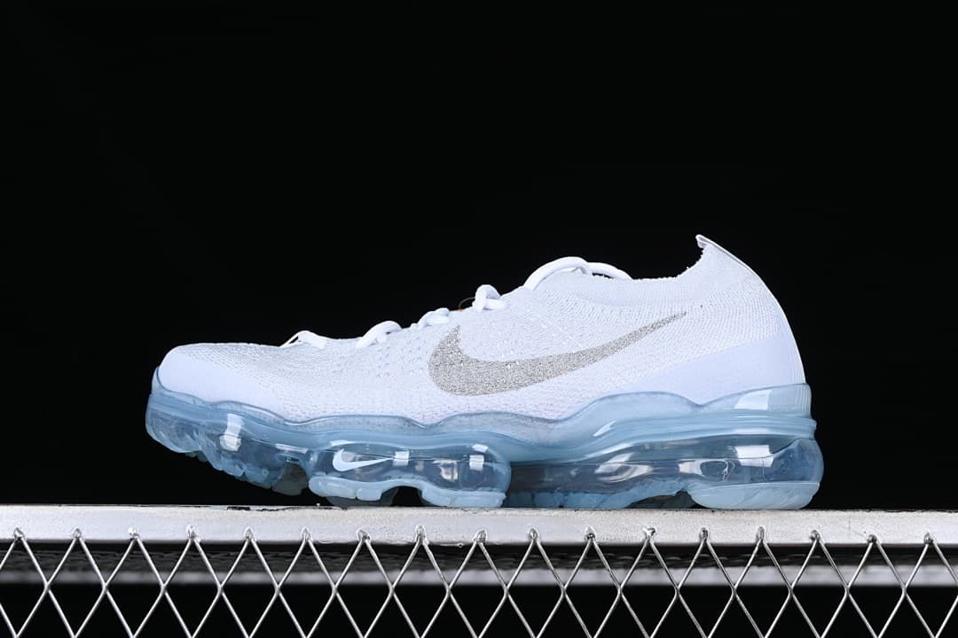White Nike Air VaporMax 2023 Flyknit sneaker with metallic-look Swoosh and translucent blue sole, side view