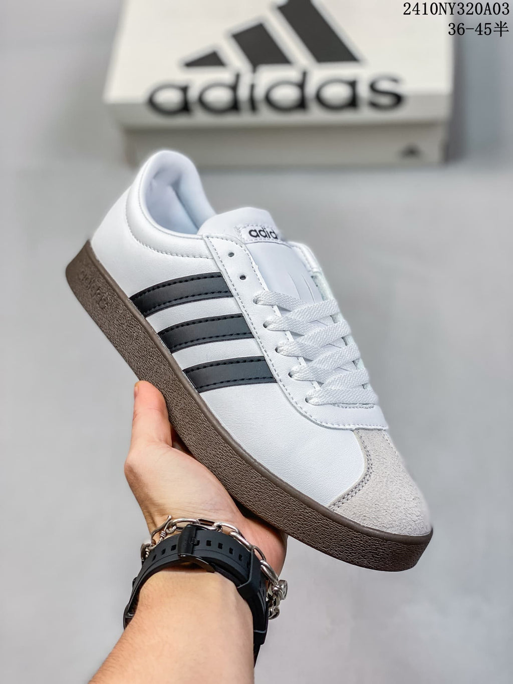 Angled side view of the white sneaker with black stripes, light-colored toe panel, and dark brown sole.