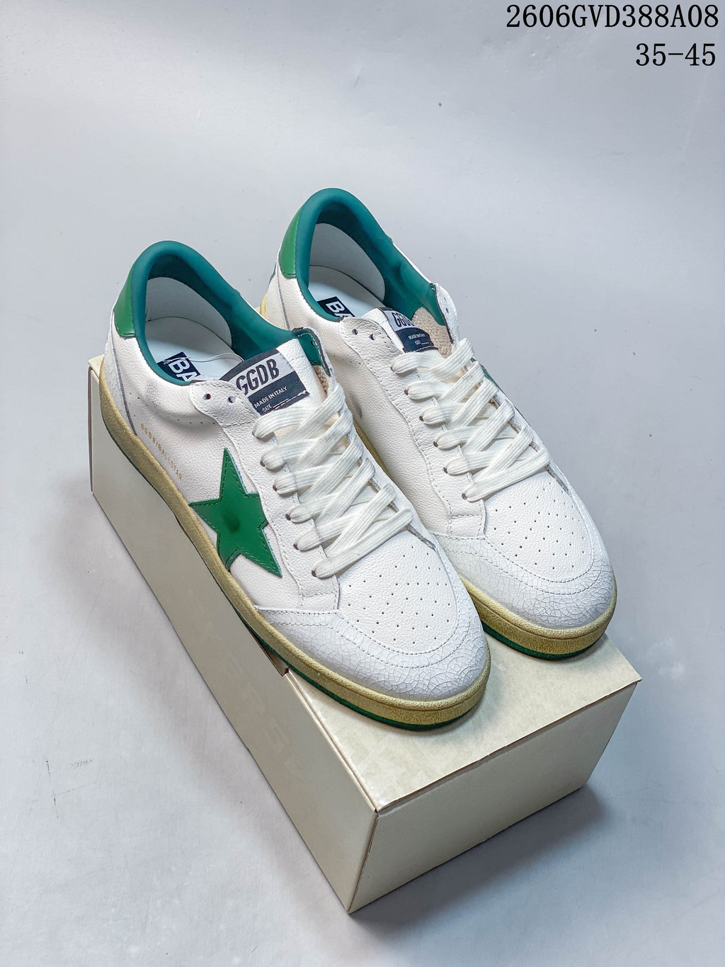 Pair of white Golden Goose Super-Star sneakers with green star details and teal accents