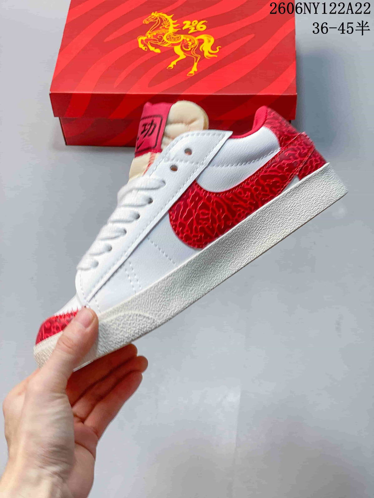 Side view of the white low-top sneaker with a red patterned Swoosh and overlays.