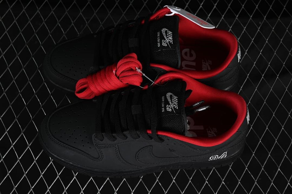 Pair of black low-top sneakers with red lining and an extra red lace set