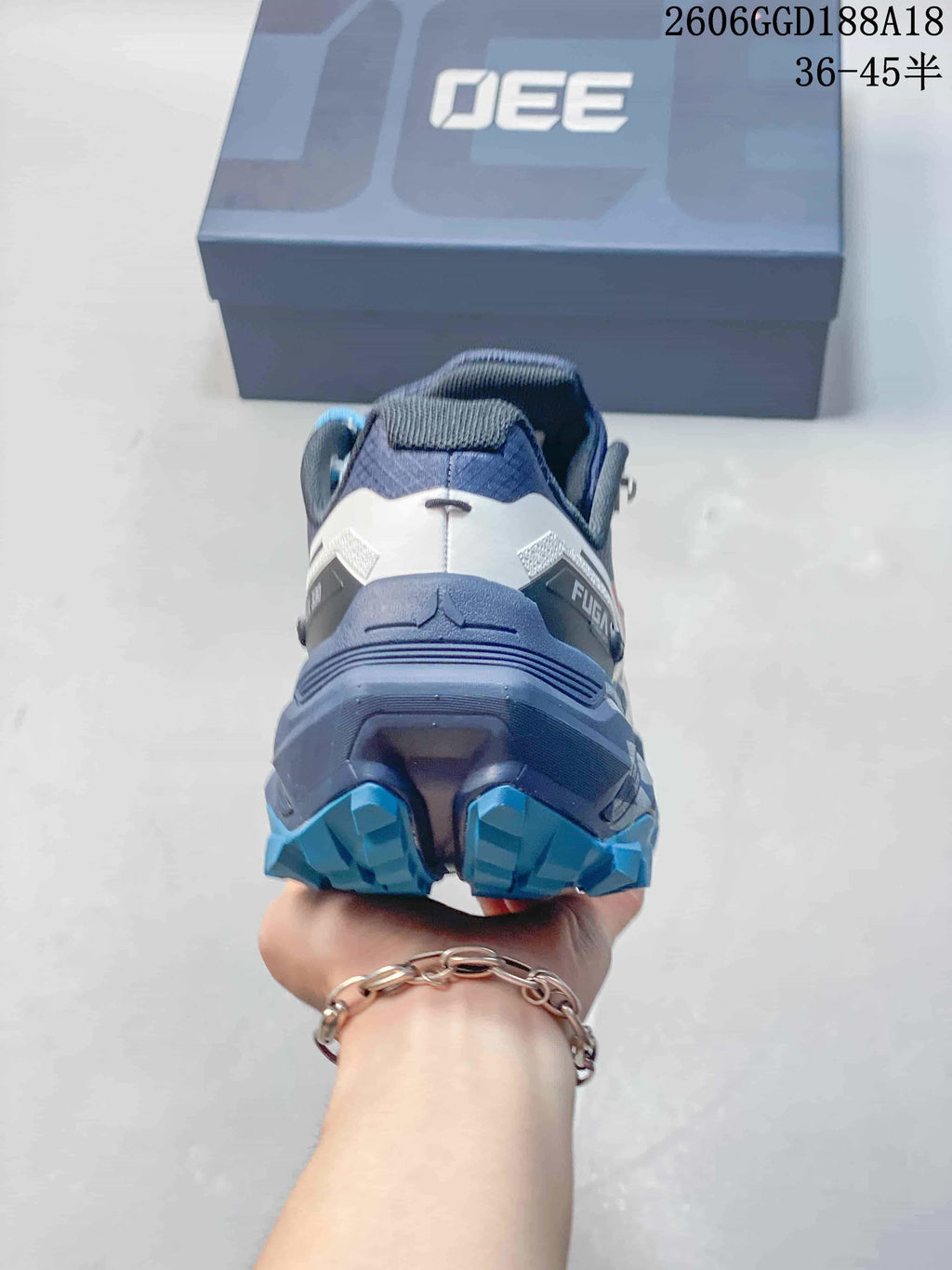 Rear view of a gray and navy trail shoe with a rugged blue outsole
