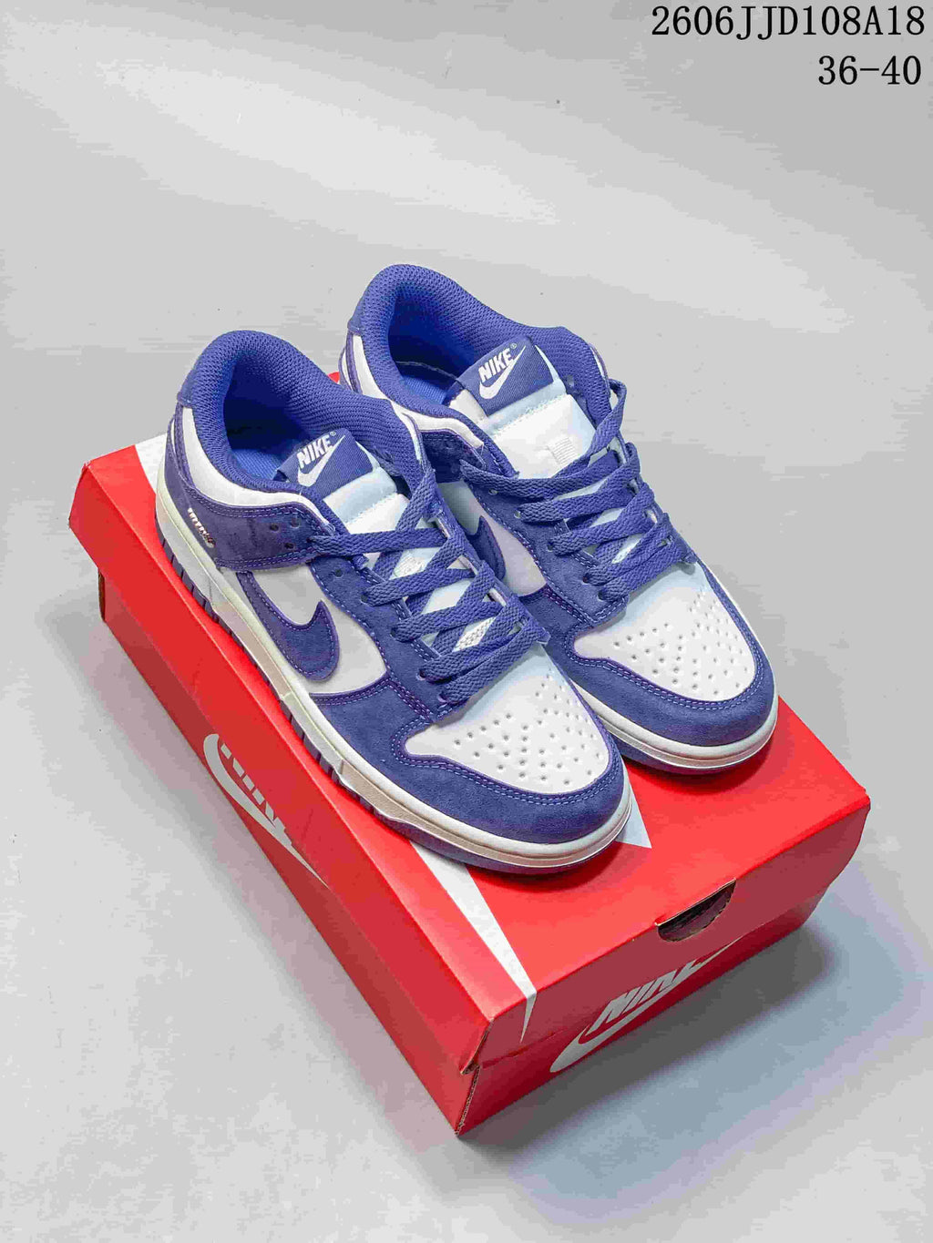 Pair of purple and white Nike SB Dunk Low Pro sneakers shown on a red shoe box.