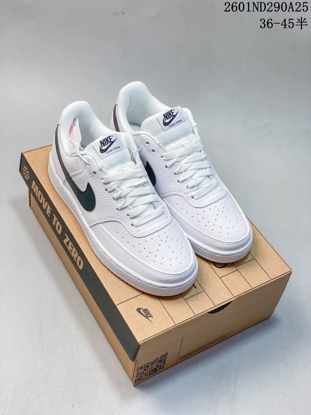 Pair of white Nike Court Vision low-top sneakers with dark Swooshes, shown on a shoebox