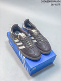 Pair of brown-grey Adidas Samba low-top sneakers with light stripes and dark laces, shown on a blue shoe box.