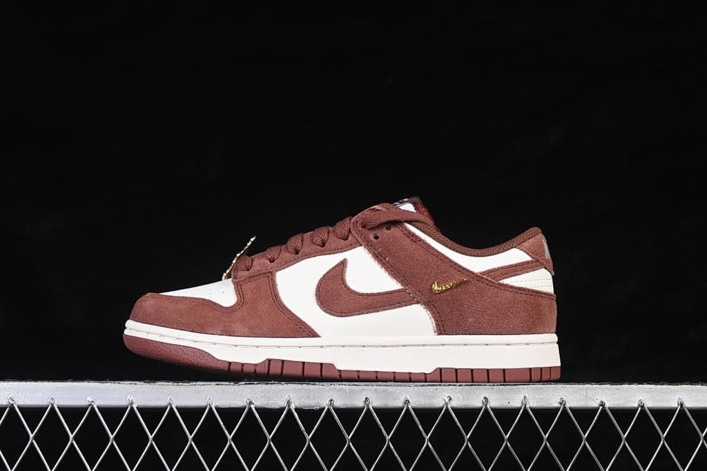 Side view of a brown and white Nike SB Dunk Low with a gold-tone mini Swoosh detail