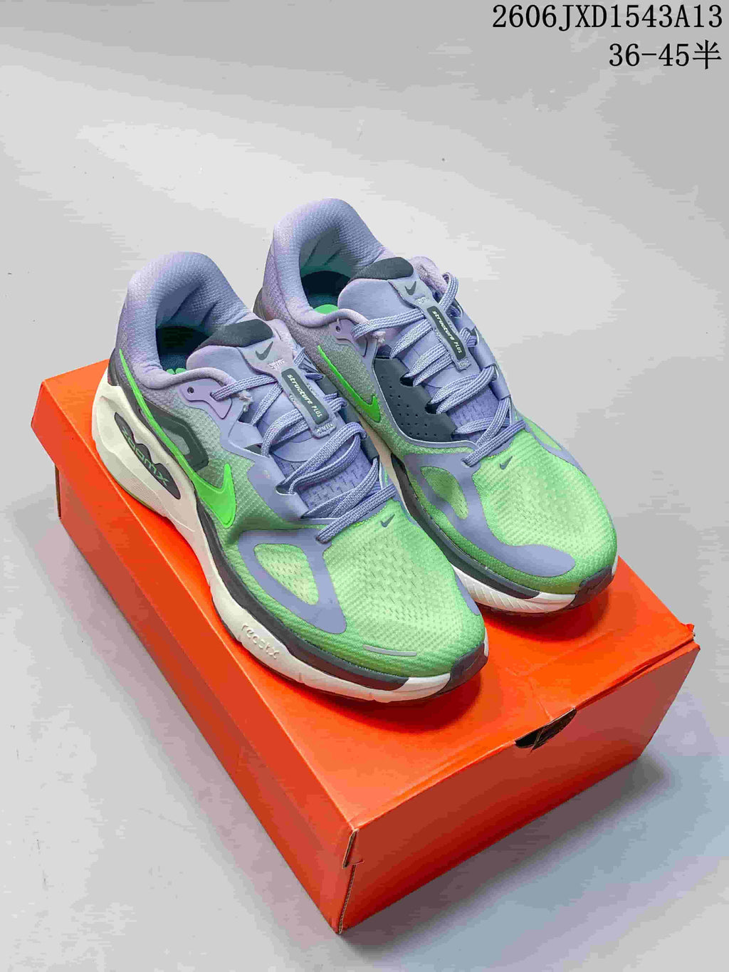 Pair of green and lavender Nike Structure Plus running shoes displayed on an orange shoe box.