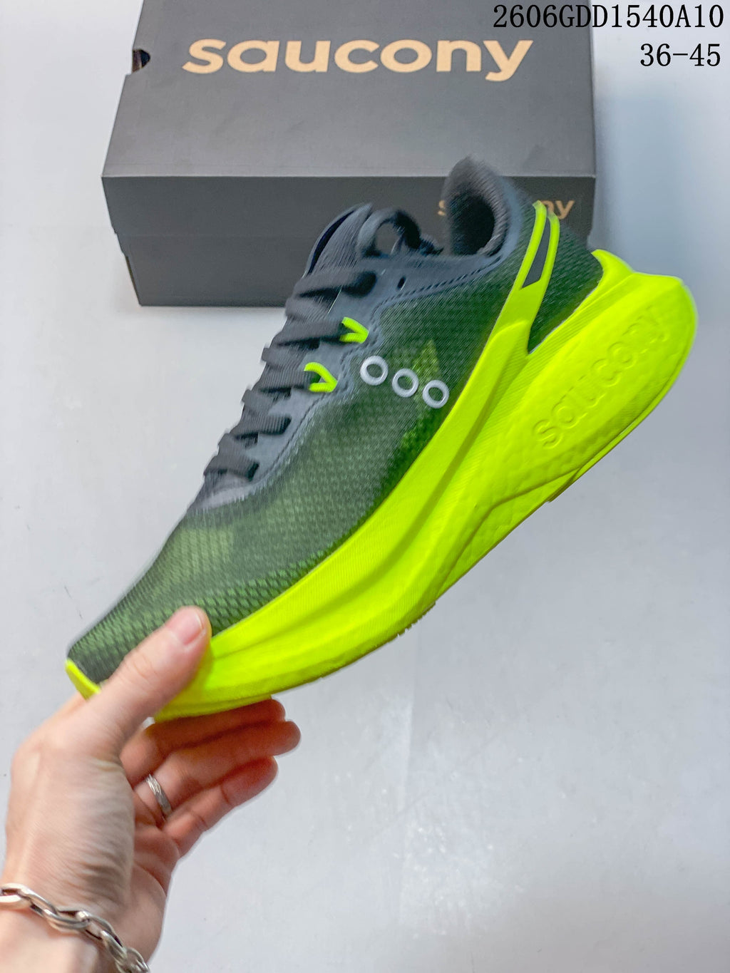 Side view of the Saucony running shoe showing the charcoal upper and bright neon yellow midsole.
