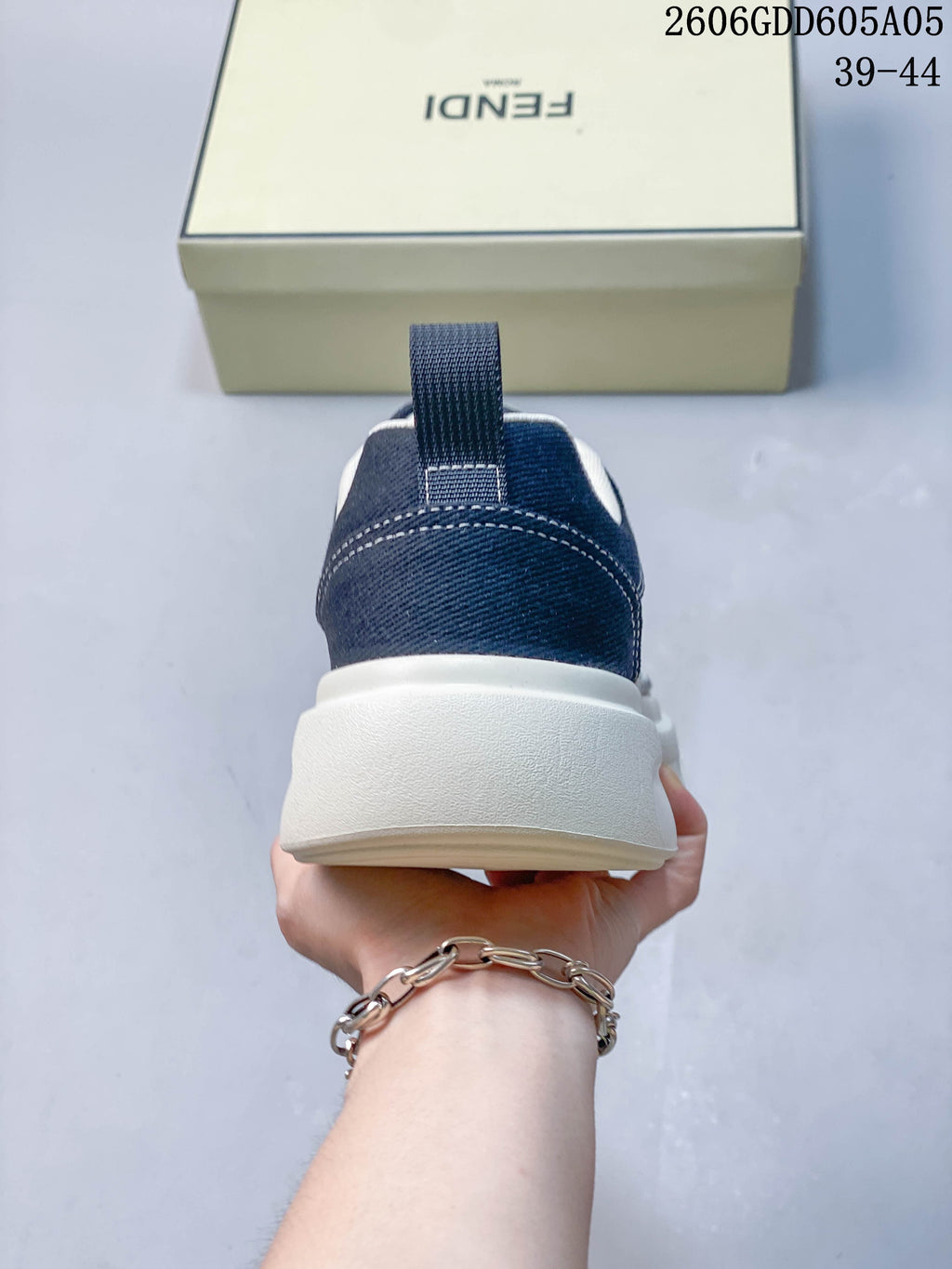 Rear view of a navy sneaker with a pull tab and thick light-colored sole.
