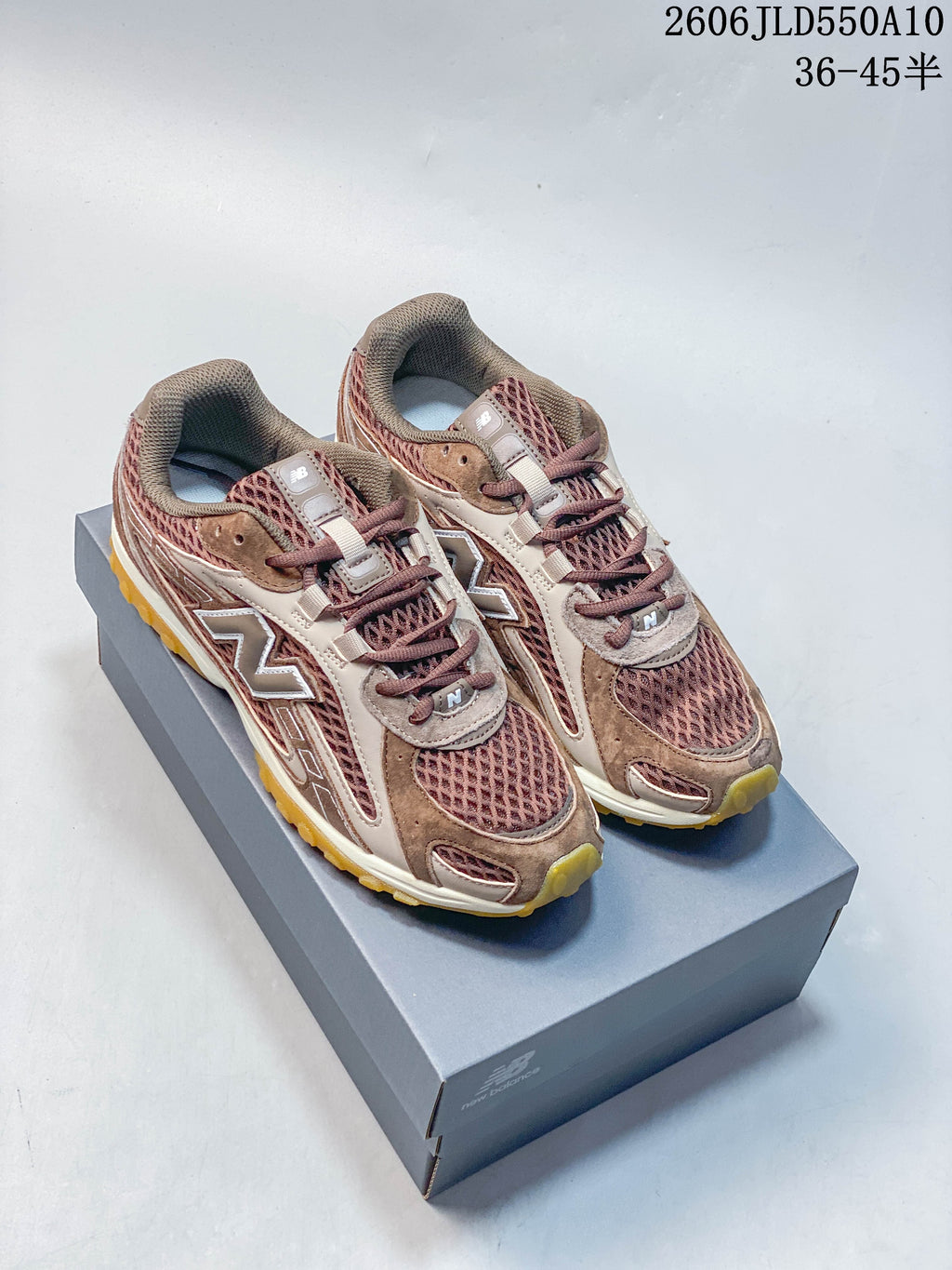Pair of brown and mauve New Balance 204L sneakers displayed on a shoebox
