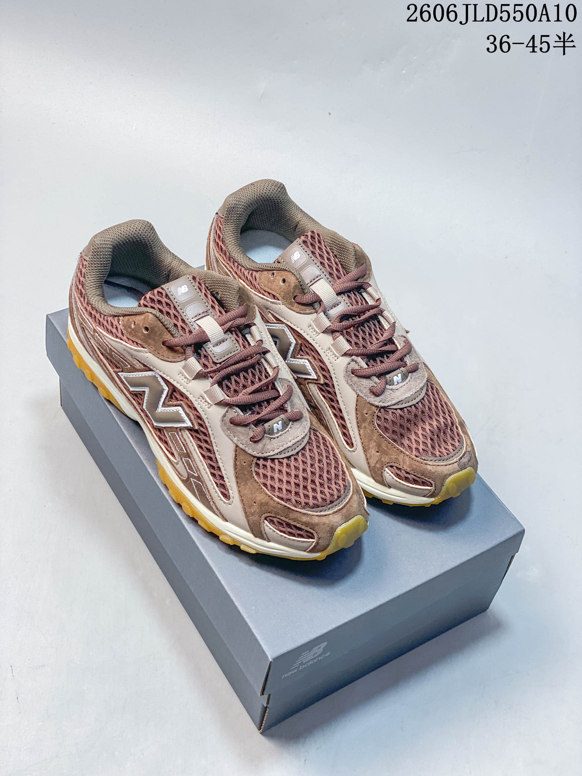 Pair of brown and mauve New Balance 204L sneakers displayed on a shoebox