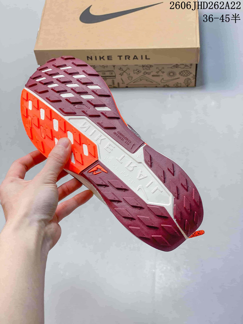 Close-up of the patterned burgundy, orange, and white outsole of a Nike Pegasus Trail shoe
