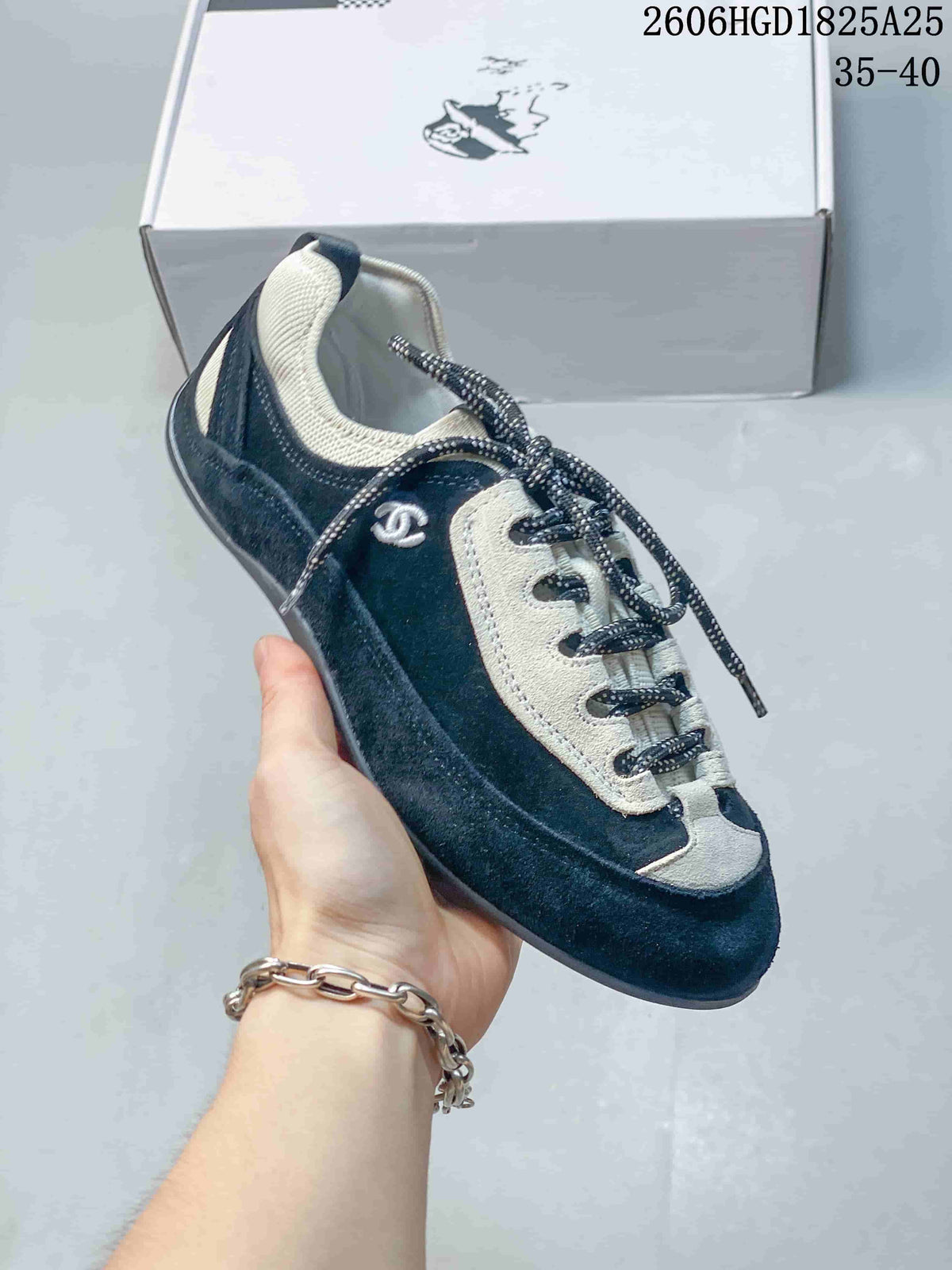 Close side view of a black and ivory low-top trainer with a rounded toe.