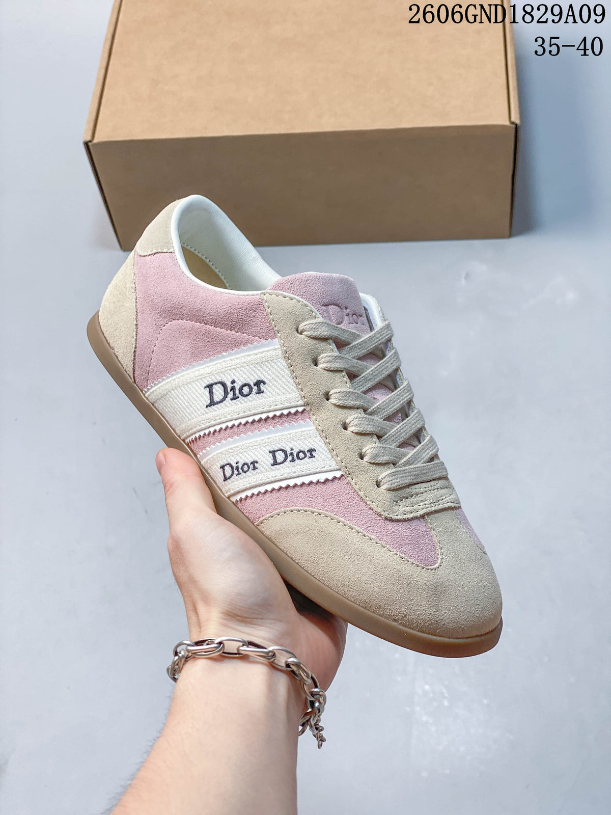 Angled side view of the pink and beige sneaker with branded side bands