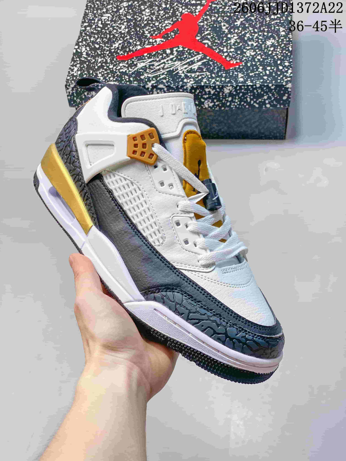 Close view of a white Jordan Spizike Low sneaker with dark blue-gray overlays and mustard lace hardware