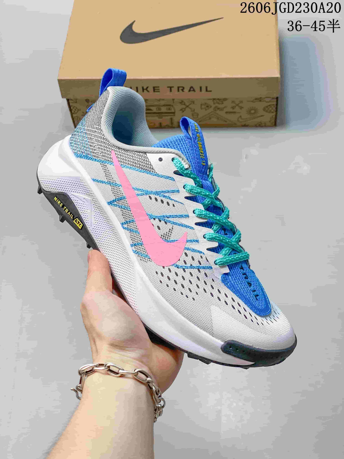 Side view of a white Nike Wildhorse 10 trail shoe with a pink Swoosh, blue accents, and turquoise laces.